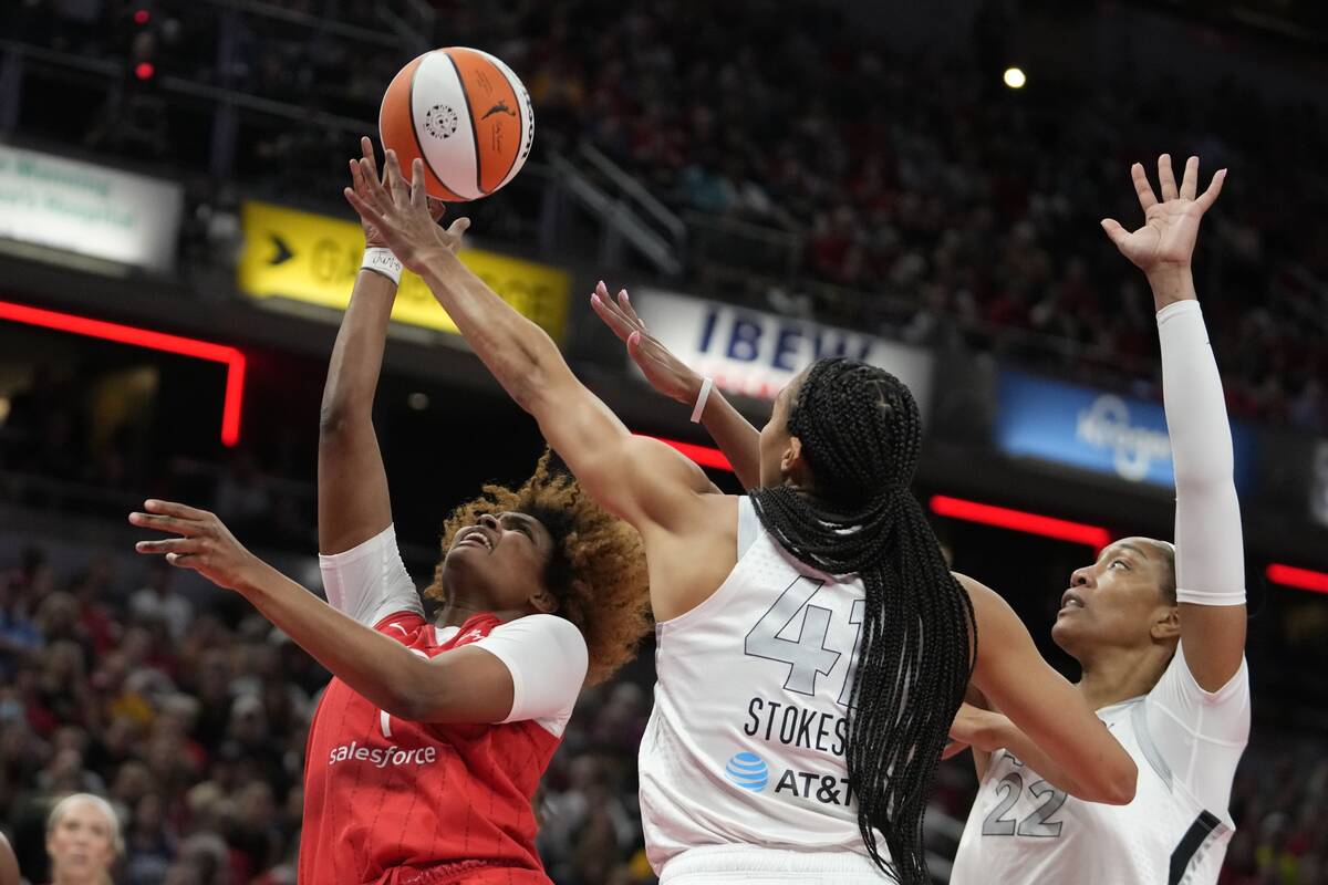 Indiana Fever's NaLyssa Smith (1) shoots over Las Vegas Aces' Kiah Stokes and A'ja Wilson (22) ...