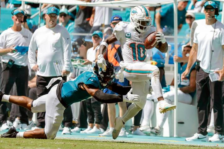 Miami Dolphins wide receiver Tyreek Hill (10) breaks a tackle attempt by Jacksonville Jaguars s ...