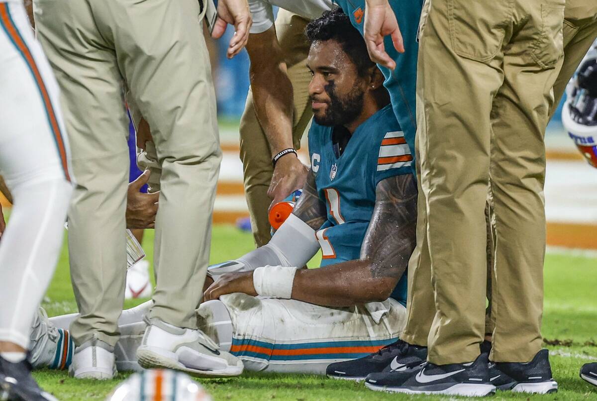 Miami Dolphins quarterback Tua Tagovailoa (1) sits on the field as he is attended to after an i ...