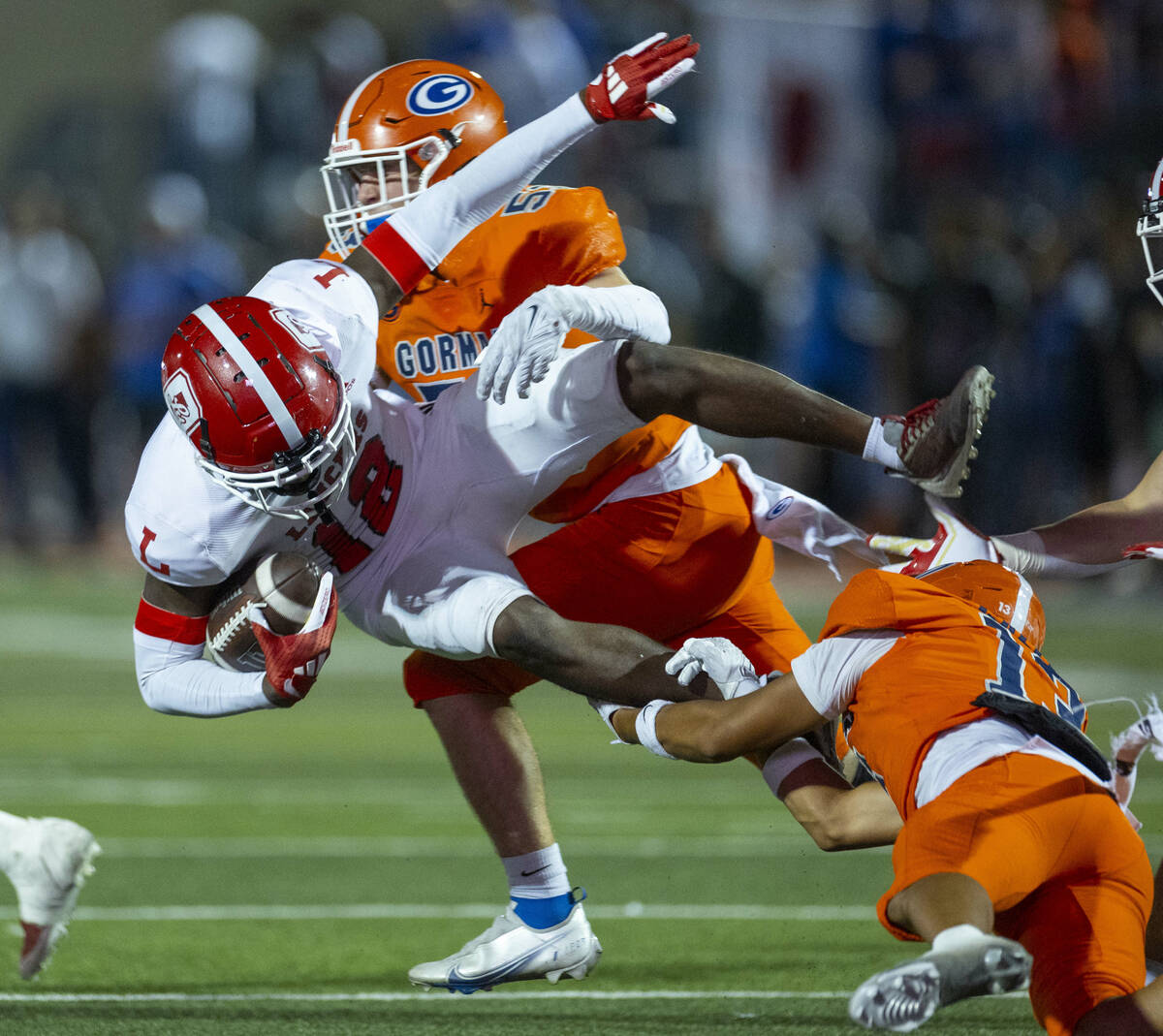 Bishop Gorman wide receiver Aizen Torres (13) upends Orange Lutheran kickoff returner Aj Campbe ...