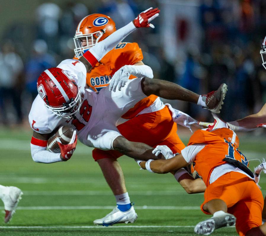 Bishop Gorman wide receiver Aizen Torres (13) upends Orange Lutheran kickoff returner Aj Campbe ...