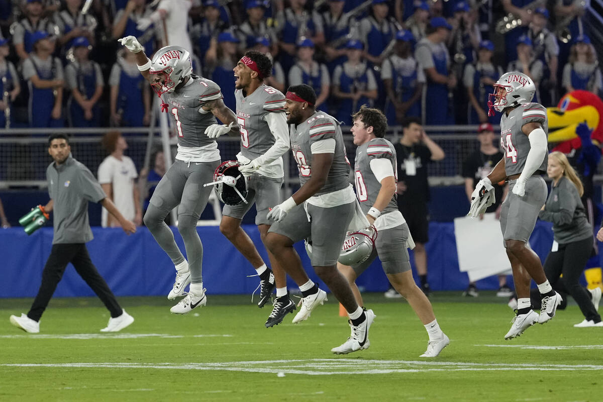 Members of UNLV run onto the field after a 23-20 win over Kansas during an NCAA college footbal ...