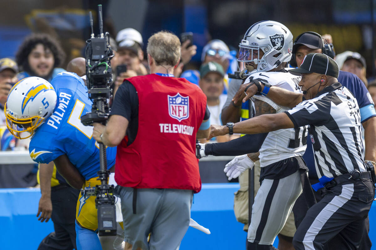 Raiders cornerback Jack Jones (18) is held back by officials on a fight with Los Angeles Charge ...