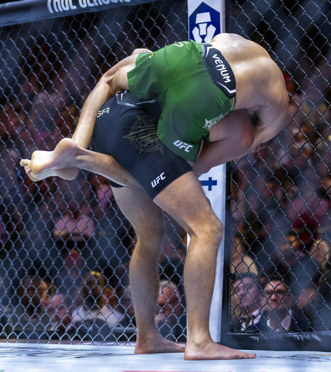 Featherweight Diego Lopes wraps up Brian Ortega from behind in their fight during UFC 306: Riya ...