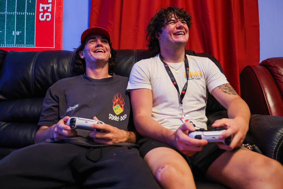 Thaddeus Thatcher, left, laughs with his brother, Christian, as they play EA Sports College Foo ...