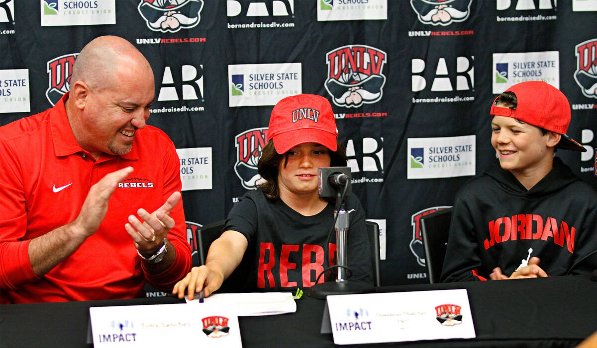 Thaddeus Thatcher, 9, center, who is battling cancer, signs during a news conference at UNLV in ...