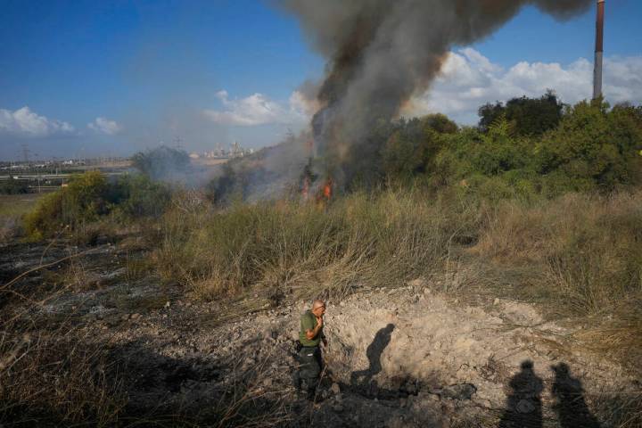 A police officer inspects the area around a fire after the military said it fired interceptors ...