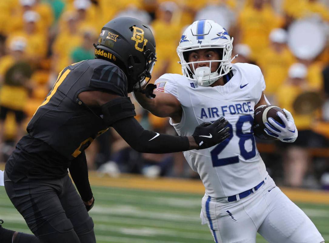 Air Force running back Aiden Calvert stiff-arms Baylor linebacker Keaton Thomas while running t ...