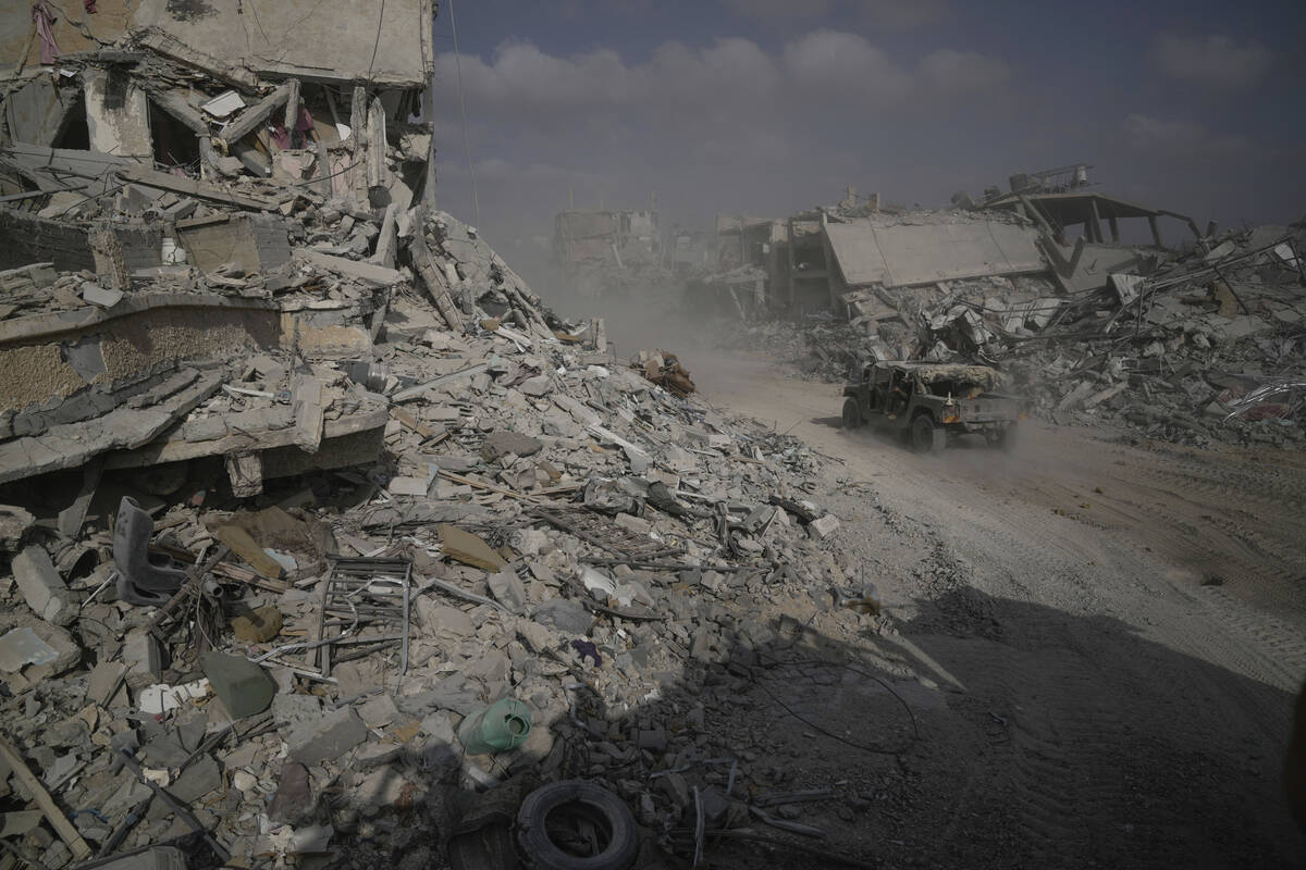 Israeli soldiers drive next to destroyed buildings following Israeli strikes during a ground op ...