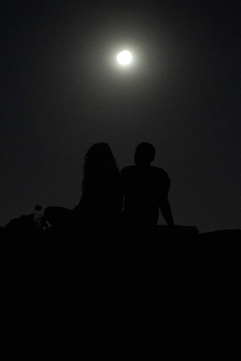 Ashley Prentiss, left, and Malik Anthony, right, watch the Harvest Moon Supermoon partial lunar ...