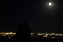 Ashley Prentiss, left, and Malik Anthony, right, watch the Harvest Moon Supermoon partial lunar ...