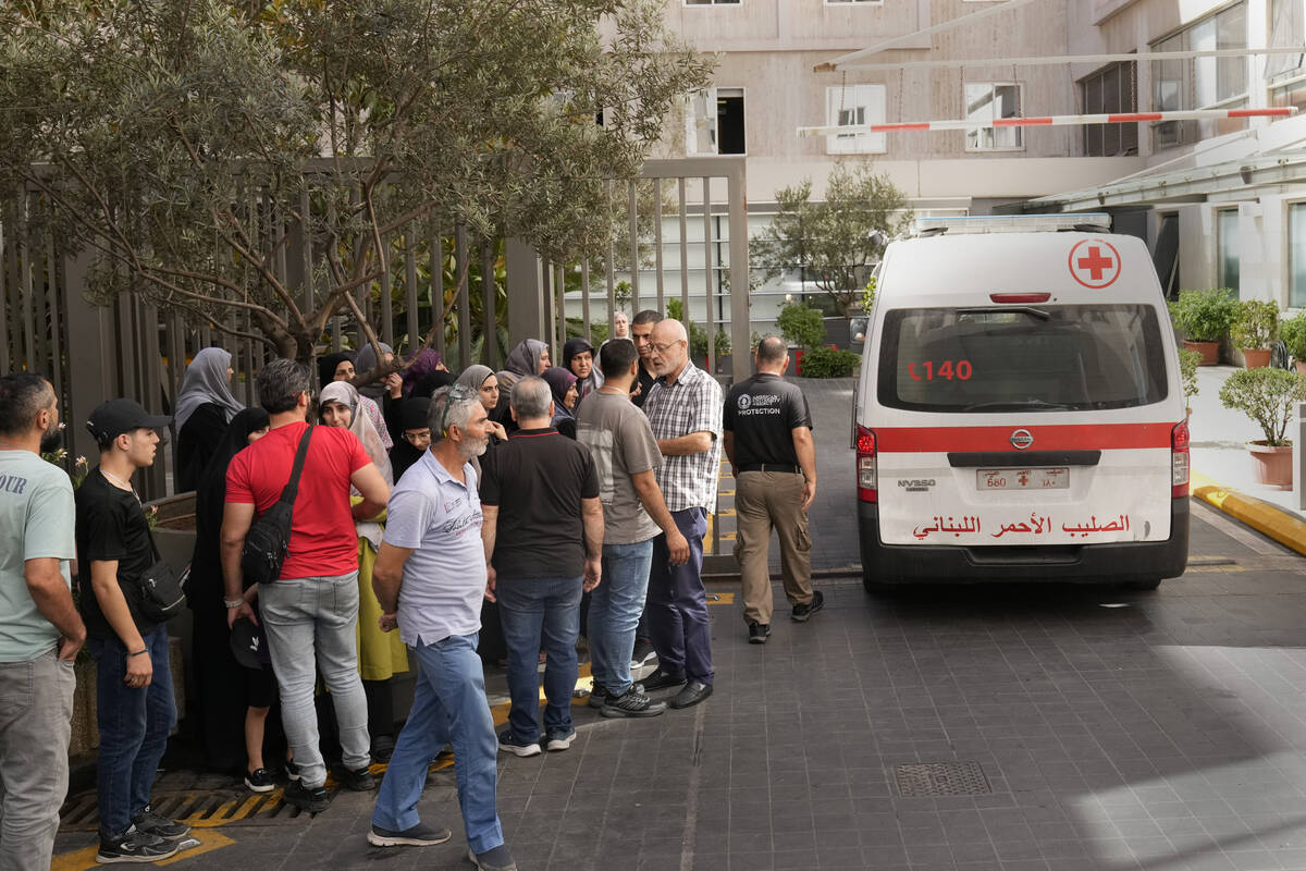 Lebanese Red Cross ambulance passes next of the families of victims who were injured on Monday ...