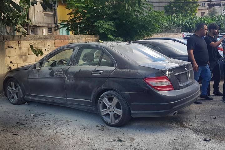 Lebanese security officers stand next of a partly damaged car after what is believed to be the ...