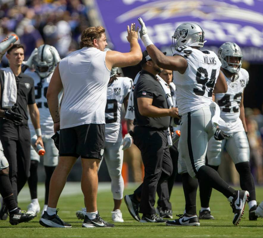 Raiders guard Jackson Powers-Johnson, left, high fives Raiders defensive tackle Christian Wilki ...