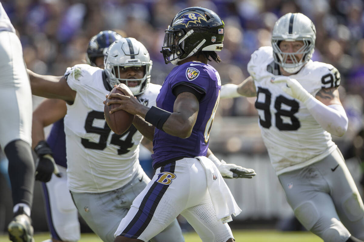 Raiders defensive tackle Christian Wilkins (94) and defensive end Maxx Crosby (98) close in on ...