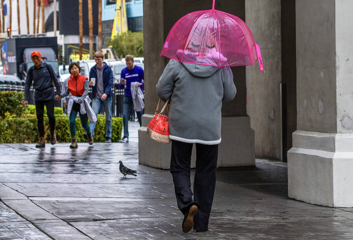 A woman walks with an umbrella along the Strip near Caesars Palace during a rainy day on Friday ...