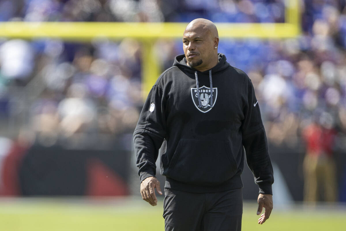 Raiders head coach Antonio Pierce smiles as he walks the field during the first half of an NFL ...