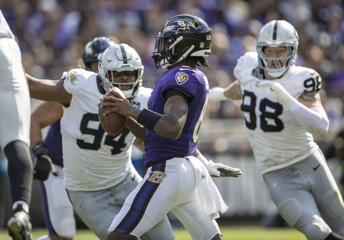 Raiders defensive tackle Christian Wilkins (94) and defensive end Maxx Crosby (98) close in on ...