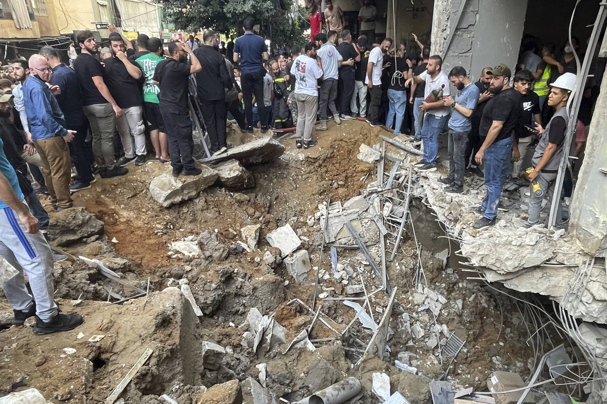 People gather at the scene of an Israeli missile strike in the southern suburbs of Beirut, Frid ...