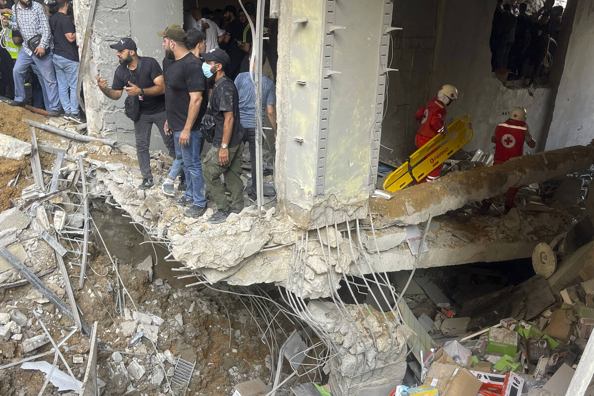 People and rescuers gather at the scene of an Israeli missile strike in the southern suburbs of ...