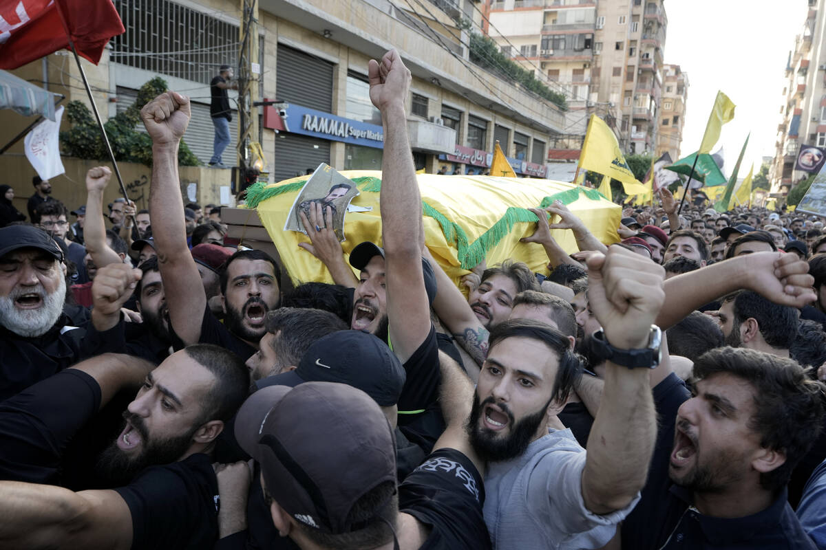 Hezbollah members carry the coffins of their comrades who were killed in Friday's Israeli strik ...