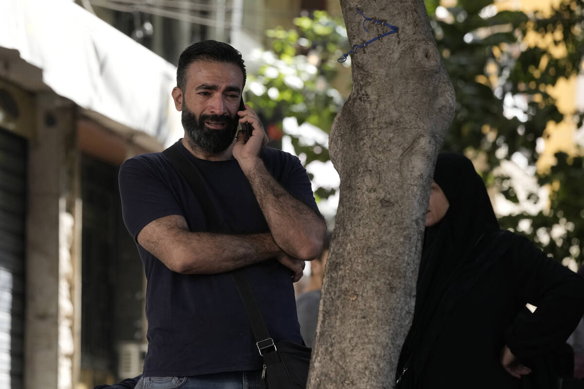 A man reacts as he speaks on the phone near the site of Friday's Israeli strike in Beirut's sou ...