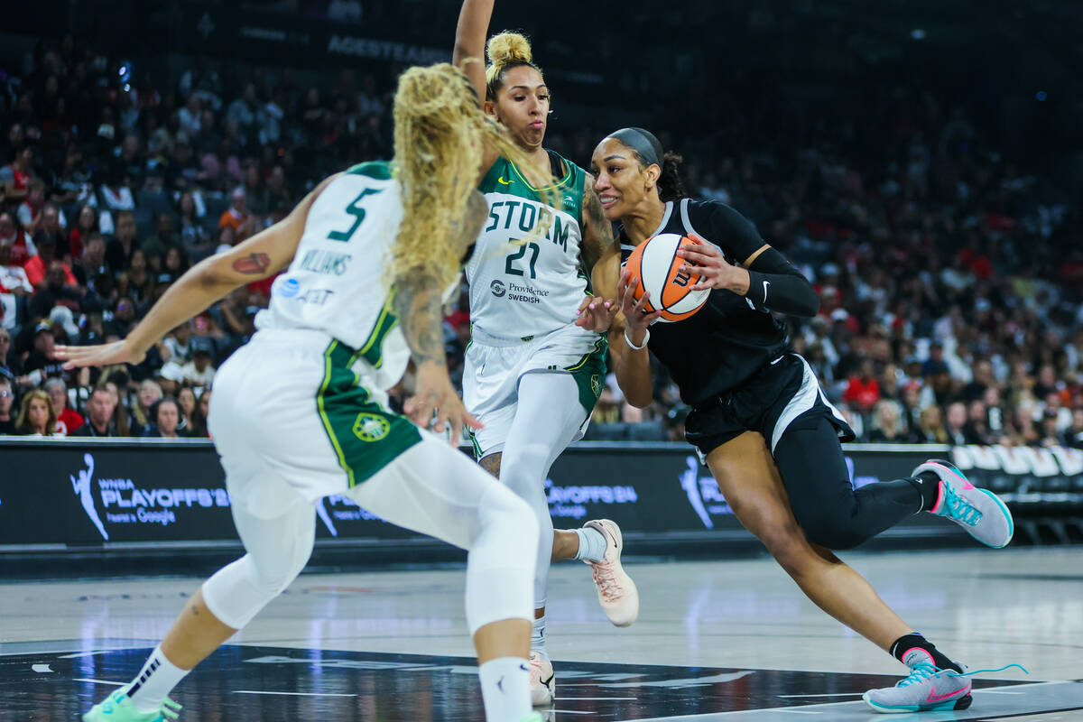 Aces center A'ja Wilson (22) drives the ball through Seattle Storm center Mercedes Russell (21) ...