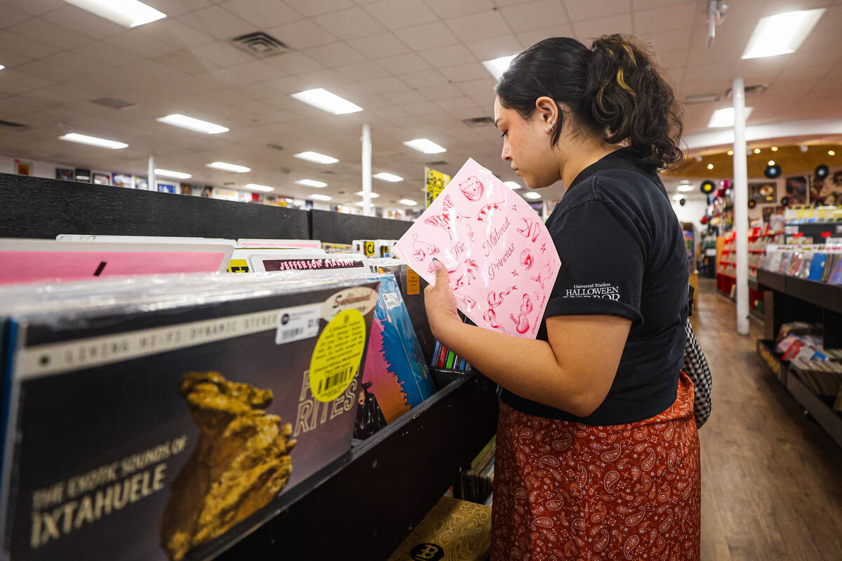 A Chappell Roan fan sorts through vinyls while holding Chappell Roan themed stickers during a l ...