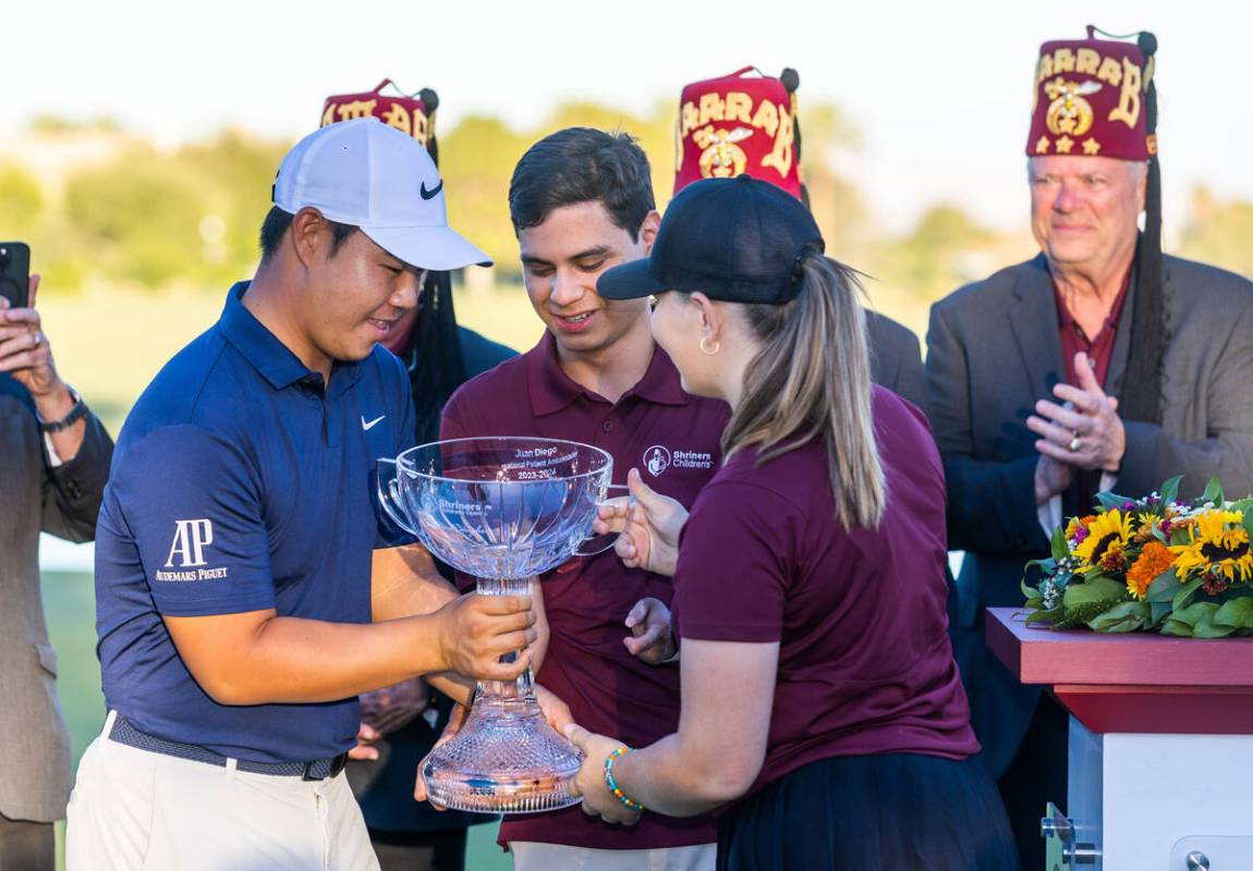 FILE - Tom Kim is handed the winning trophy by international patient ambassadors Juan Diego and ...