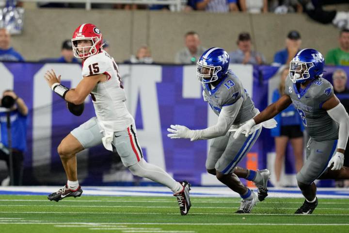 Georgia quarterback Carson Beck (15) is chased by Kentucky linebackers J.J. Weaver (13) and Jam ...