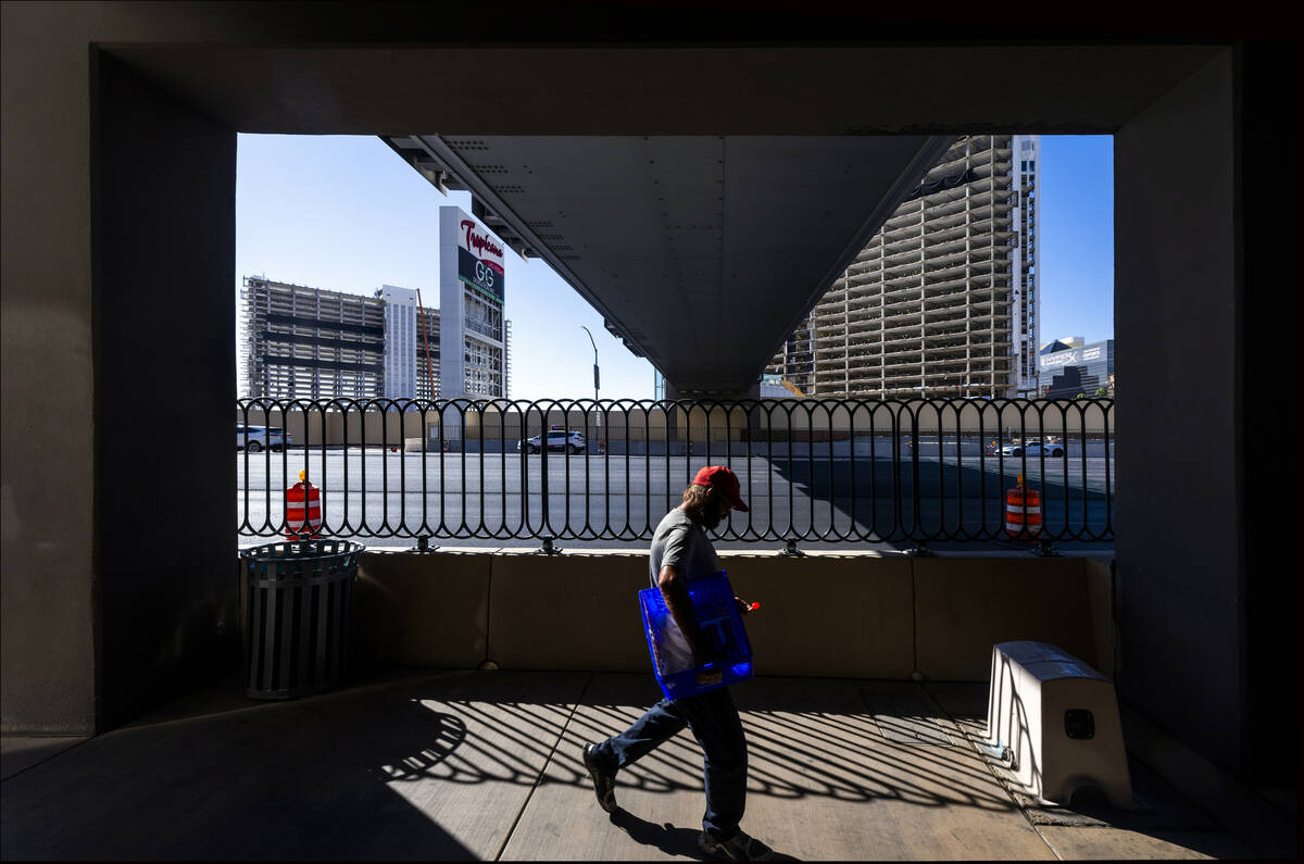 A man walks under the now-closed pedestrian bridge from the MGM Grand as preparations for the u ...