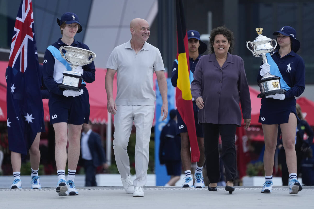 Former Grand Slam champions Andre Agassi and Evonne Goolagong Cawley walk with ball kids carryi ...