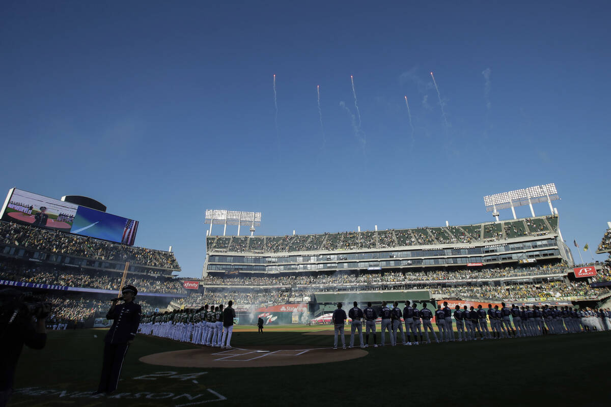 FILE - Fans at Oakland Coliseum listen as the national anthem is performed before an American L ...