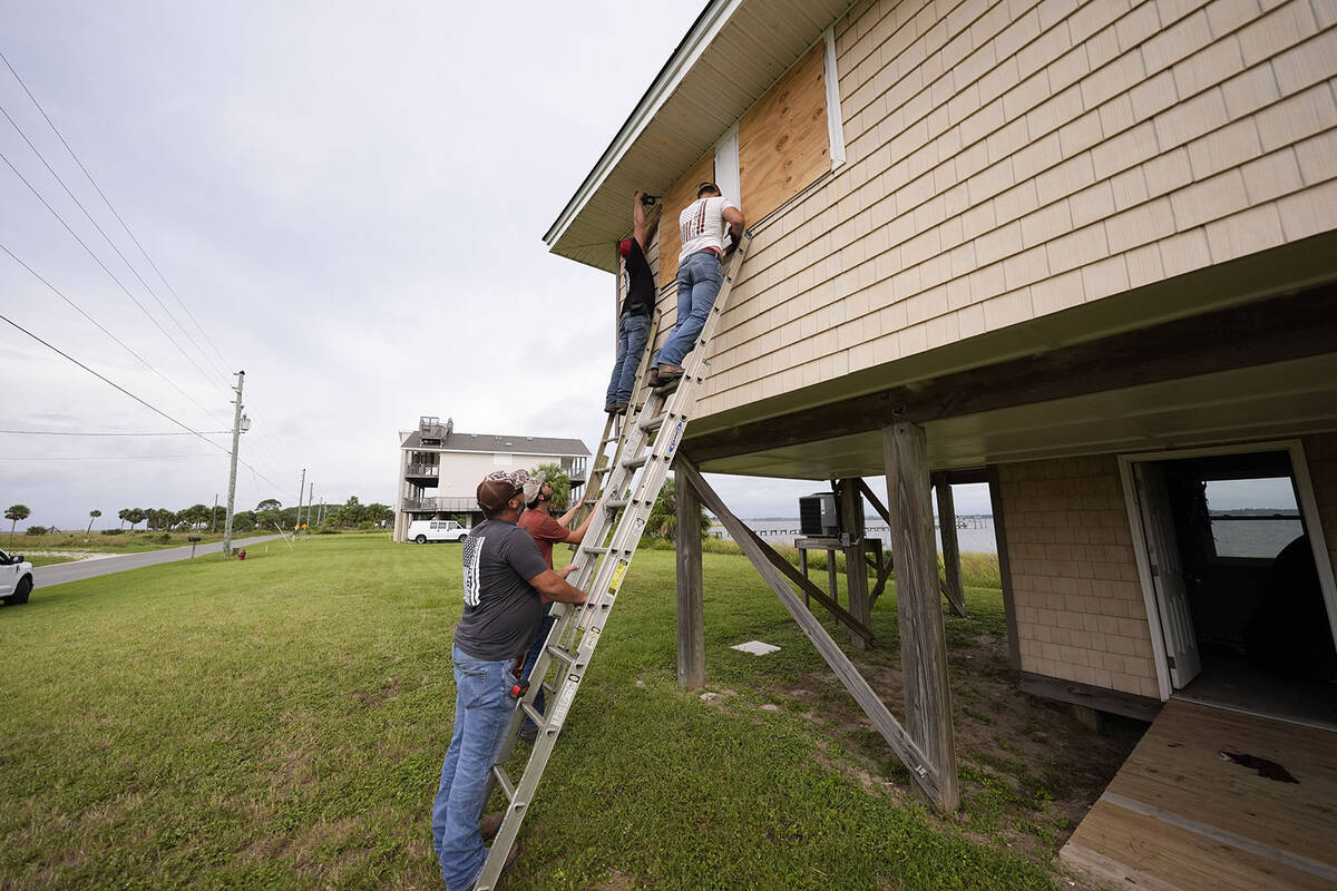 Jerry McCullen, top of ladder left, and Carson Baze, top of ladder right, put plywood over the ...