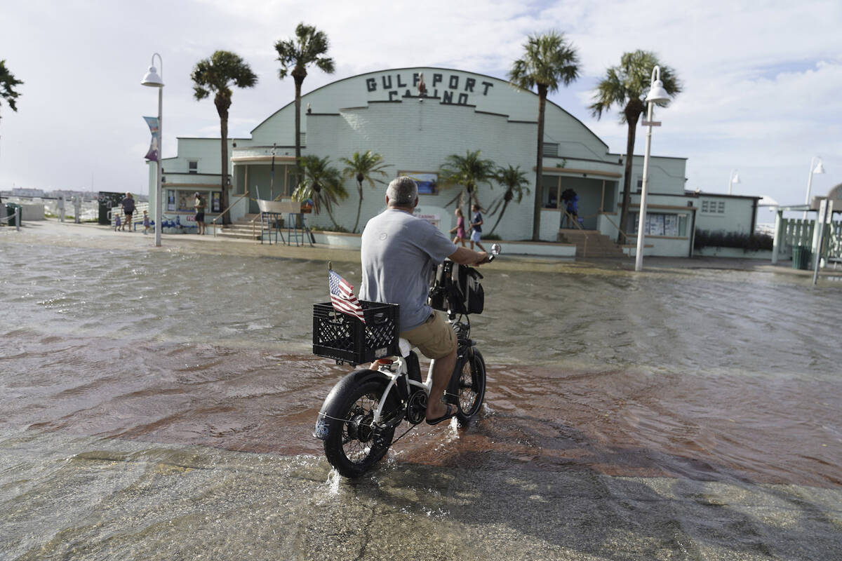 Louis Ward, 57, rides his bike along the the Gulfport waterfront as it takes on water as Hurric ...