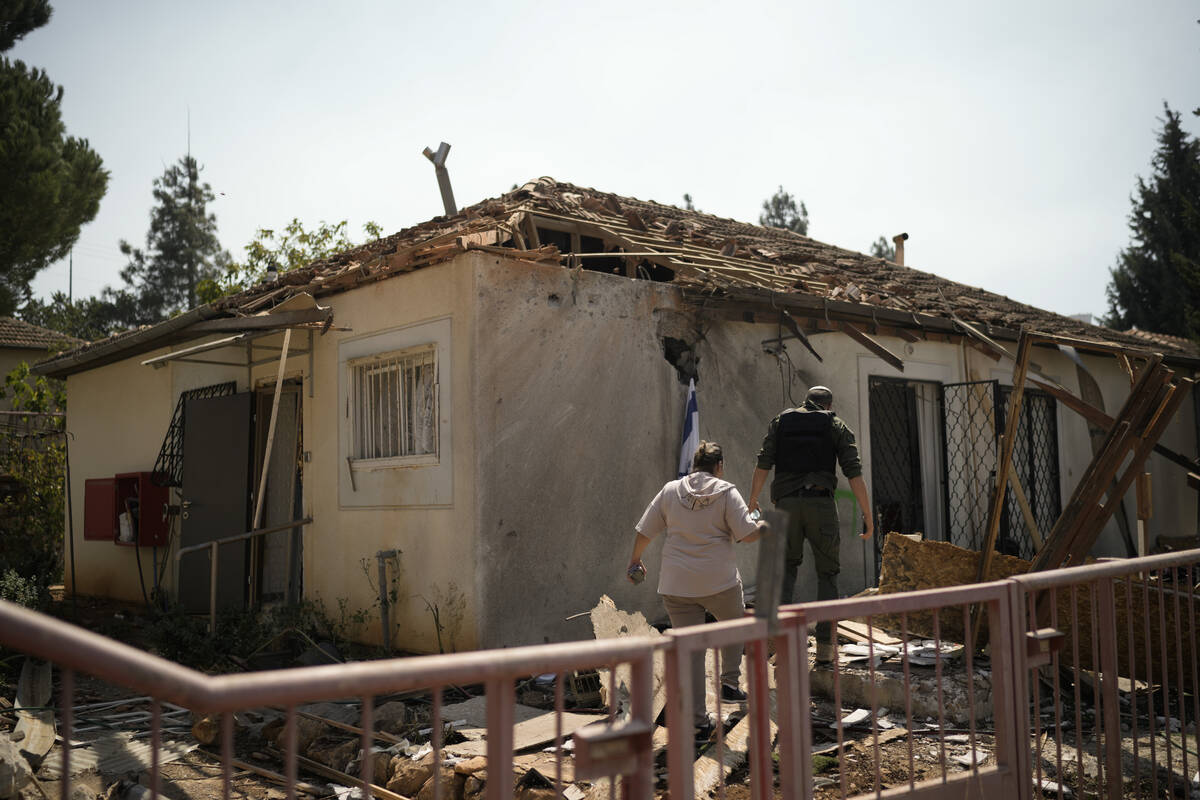 People look at a damaged house that was hit by a rocket fired from Lebanon, near Safed, norther ...