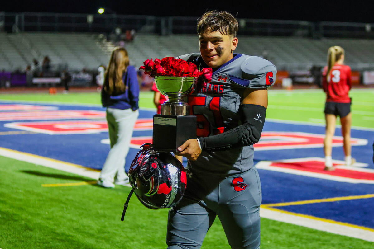 Coronado defensive lineman David Merabyan brings the St. Rose trophy into the locker room follo ...