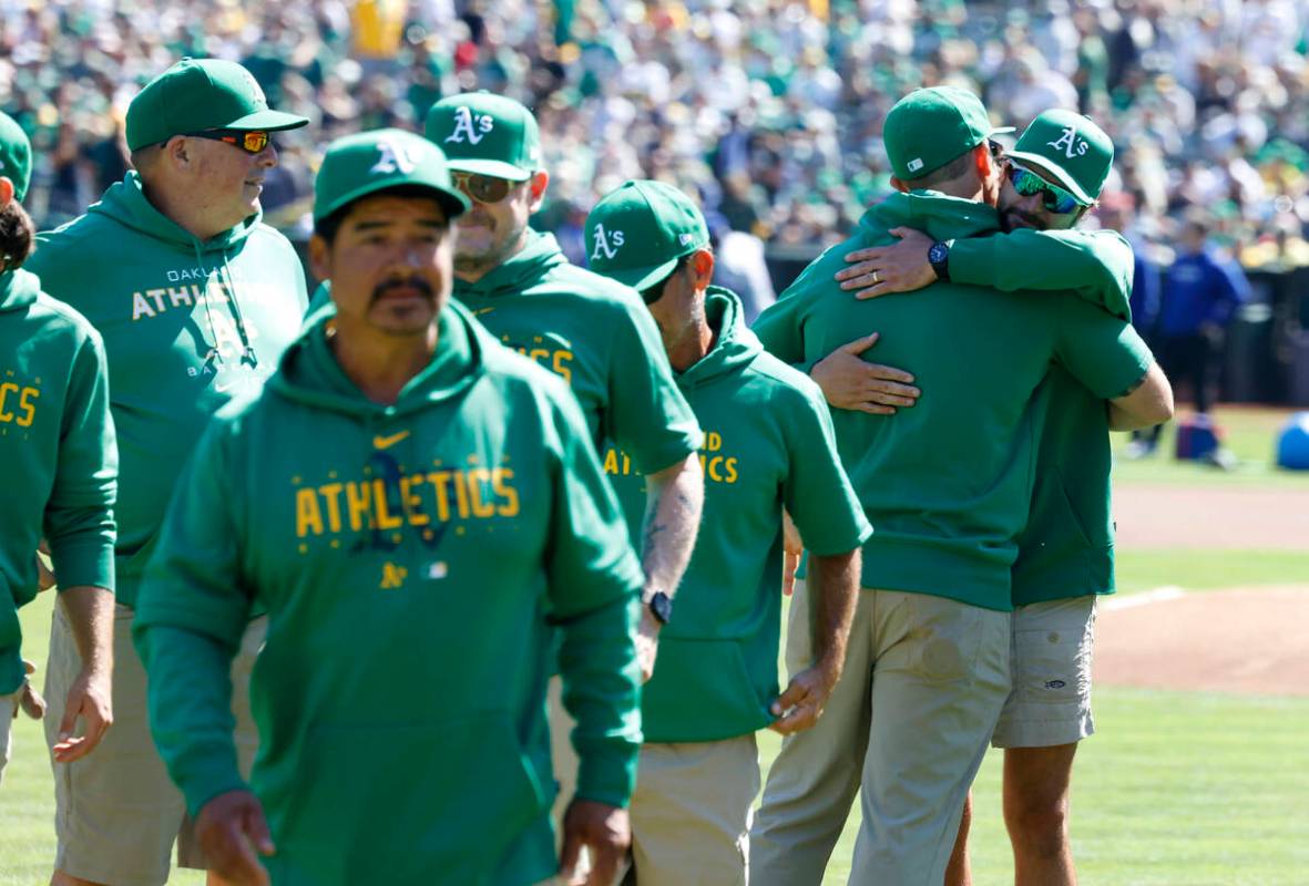 Oakland Athletics grounds crew hug each other as they leave the field after the final home game ...