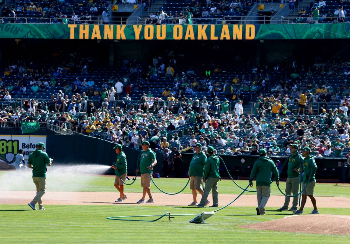 Oakland Athletics grounds crew with hose prepare the infield before the final home game against ...