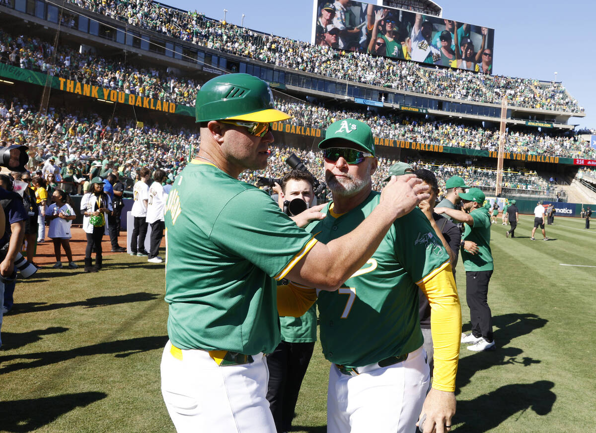 Oakland Athletics manager Mark Kotsay, right, and first base coach Bobby Crosby comfort each o ...