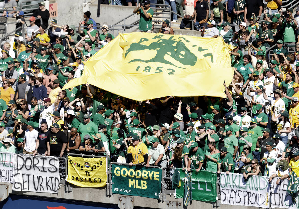 Oakland Athletics fans post signs and wave a flag as they watch the final home game against the ...