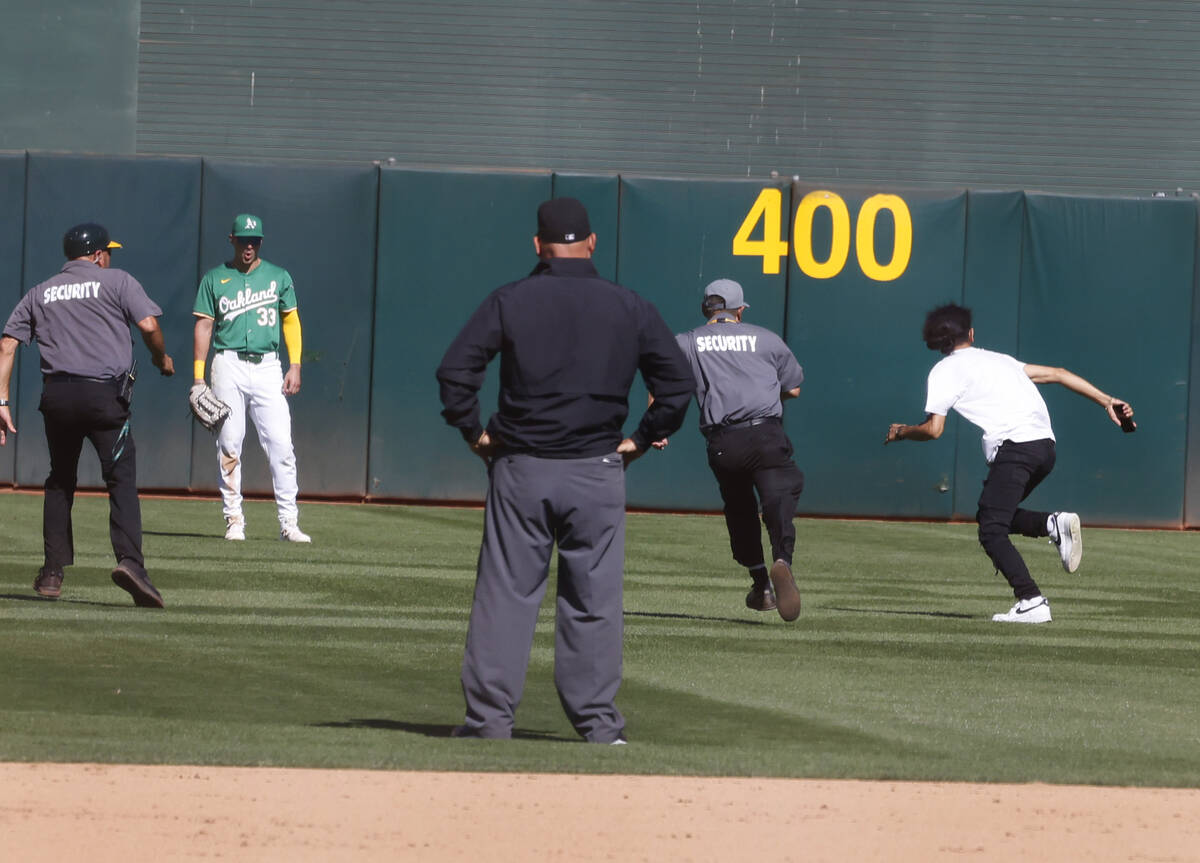 A fun runs to left field while being pursued by security guards as Oakland Athletics play again ...