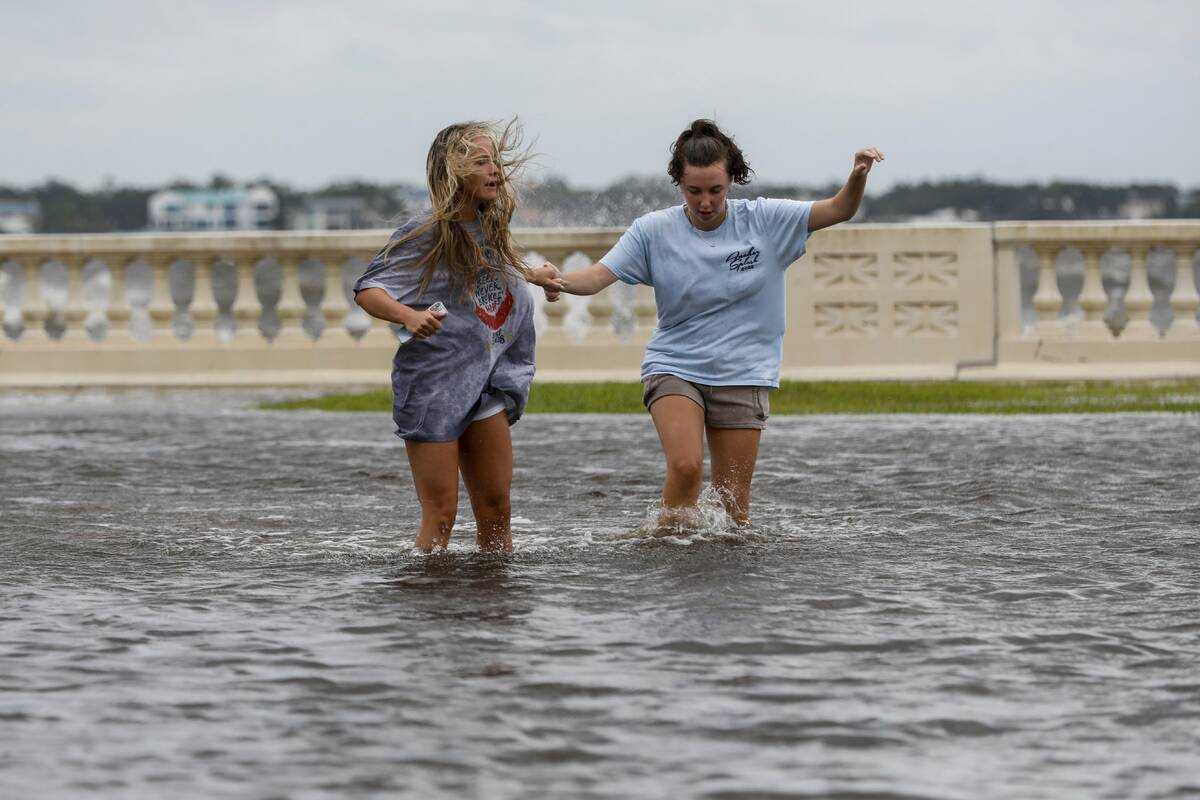 Camryn Frick, left, and Jillian Sternick, both 22, and of Tampa, hold hands as they cross a flo ...