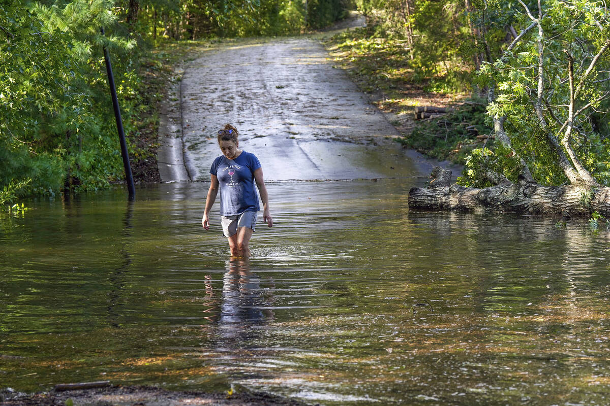 Teresa Elder walks through a flooded Sandy Cove Drive, from Hurricane Helene Friday, Sept. 27, ...