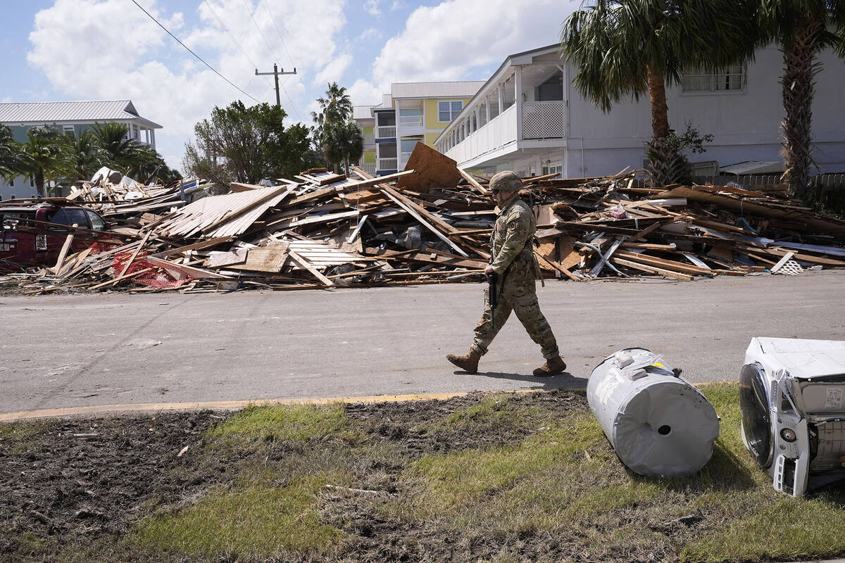 Florida National Guard Specialist Jacob Norman walks past piles of debris as he patrols in the ...