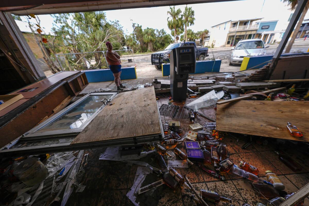 Kegan Ward, assistant manager of Swami Spirits, walks through debris of the damaged store in th ...