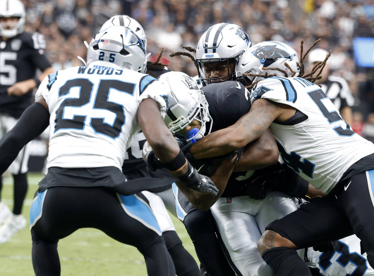 Raiders running back Zamir White (3) is sandwiched between Carolina Panthers running back Jonat ...