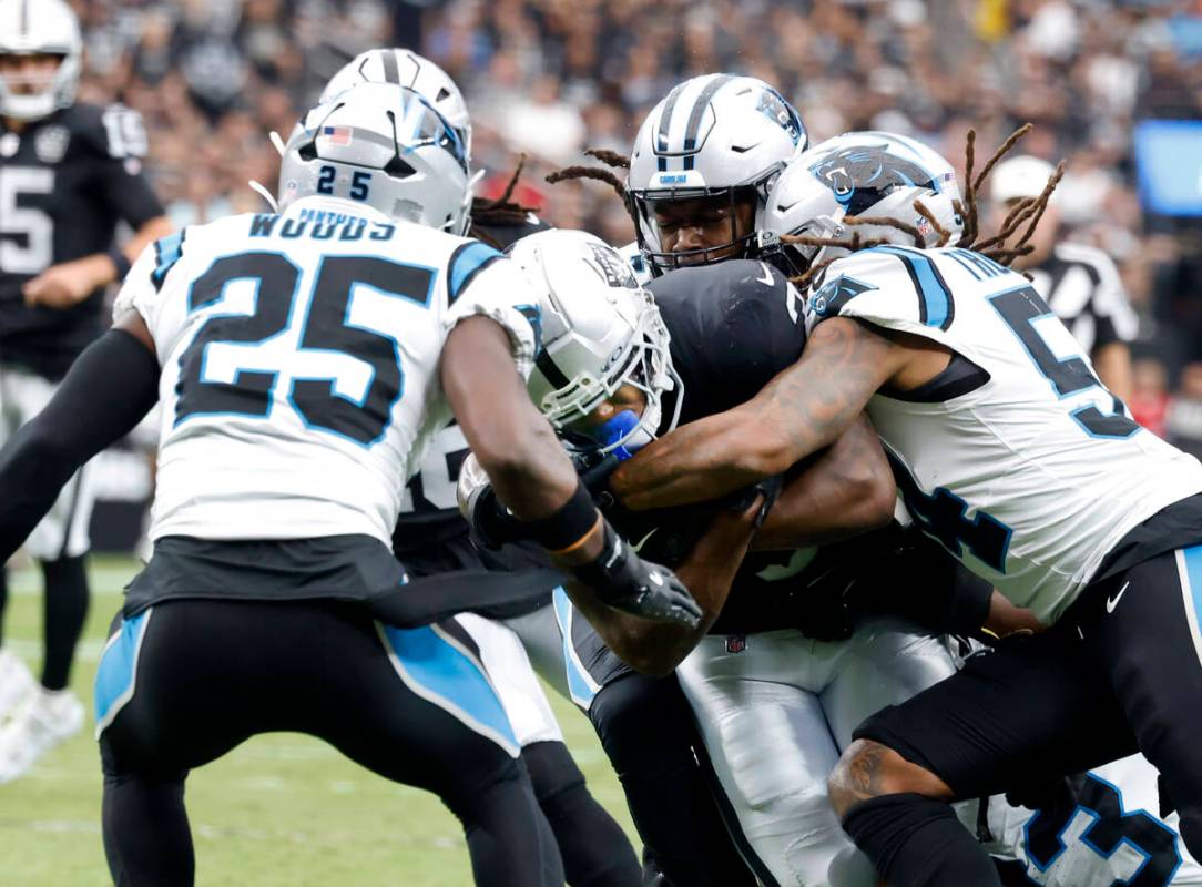 Raiders running back Zamir White (3) is sandwiched between Carolina Panthers running back Jonat ...