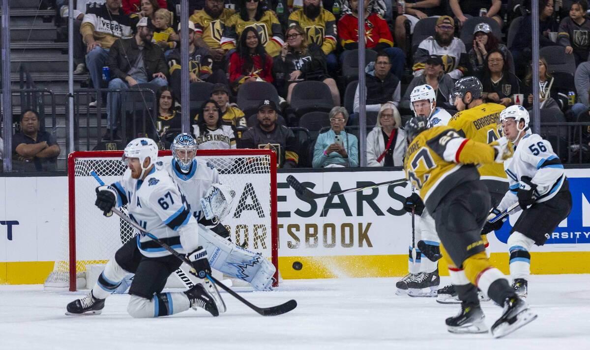 Golden Knights defenseman Shea Theodore (27) takes a shot at the net and Utah Hockey Club goalt ...