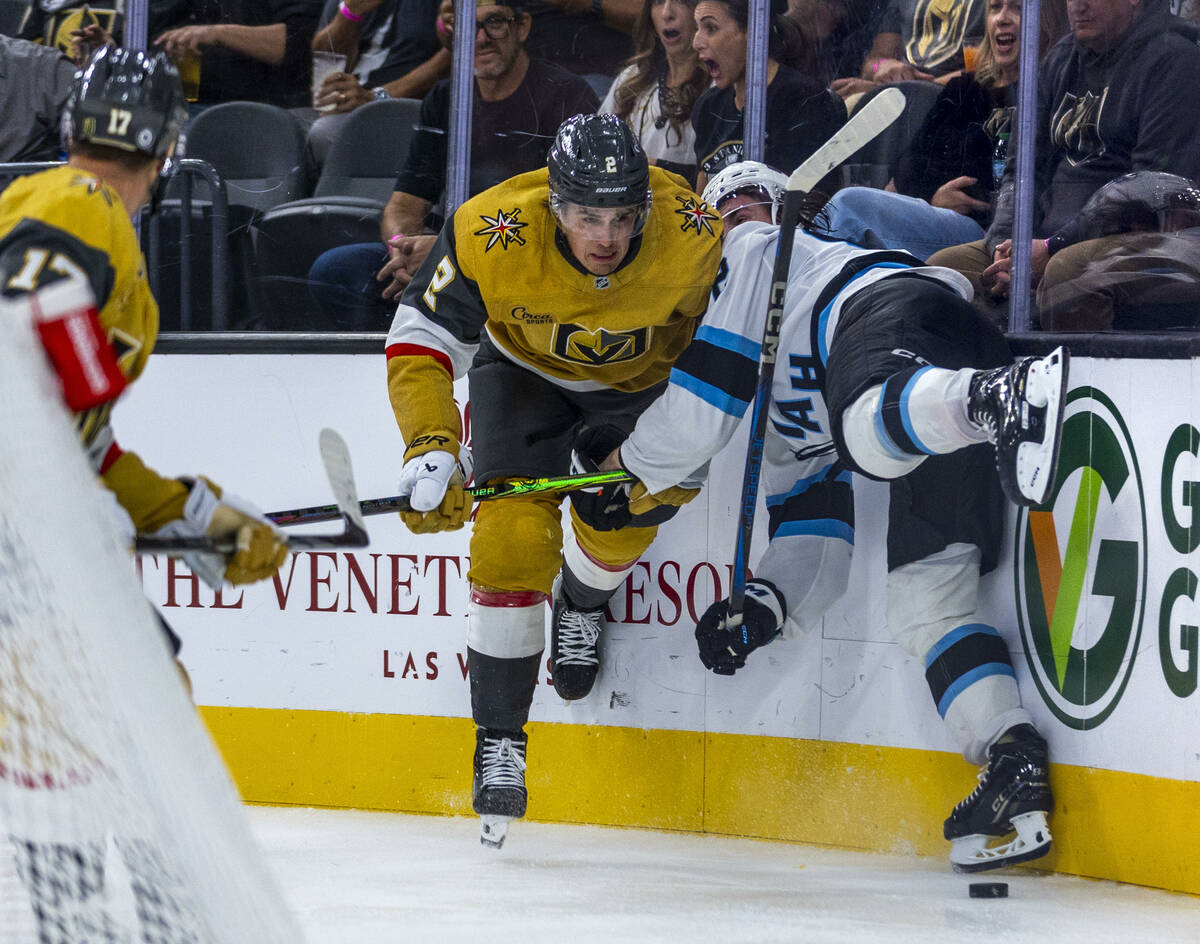 Golden Knights defenseman Zach Whitecloud (2) checks Utah Hockey Club forward Logan Cooley (92) ...